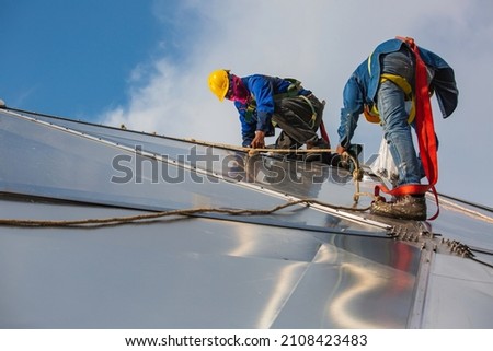Male workers rope access height safety connecting with a knot safety harness, roof fall arrest and fall restraint anchor point systems ready to ascending, construction site oil tank dome Royalty-Free Stock Photo #2108423483