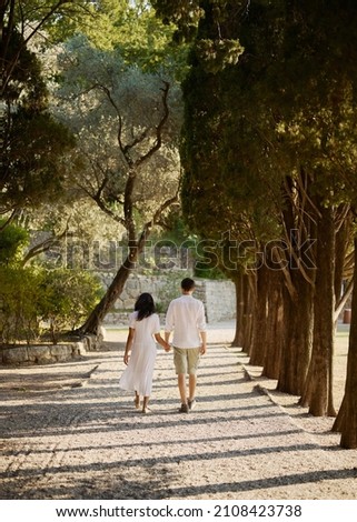 Tourists on vacation. Holidays. Park. Summer day, good weather, beautiful warm sunlight. Couple in white cotton clothes. Natural, colorful and bright picture.