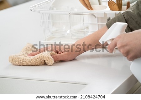 Woman housewife is doing the spring cleaning at home kitchen with using rag, spraying bottle cleaner to wipe the counter table surface. Royalty-Free Stock Photo #2108424704