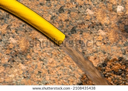 a jet of water from a hose on the background of a granite wall. background picture. space for printing text.