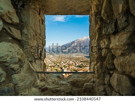 A picturesque view of the city near the mountains opens from the window opening of the old stone fortress