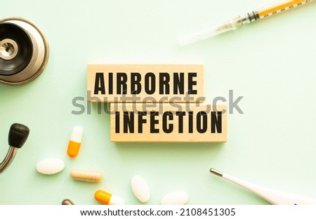 The words AIRBORNE INFECTION on a wooden cubes with a stethoscope and pills. Medical concept. Royalty-Free Stock Photo #2108451305