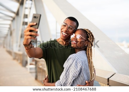 Happy smilng couple taking selfie with phone outdoors. Boyfriend and girlfriend having fun outdoors	