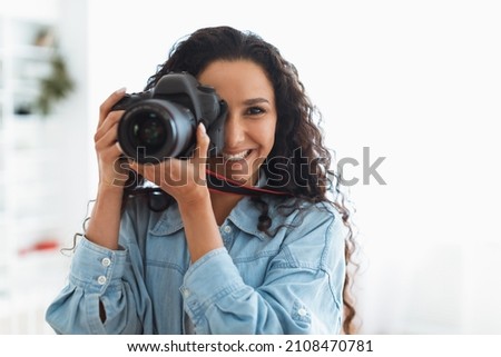 Happy Photographer Lady Taking Photo Holding Camera Near Face And Smiling Standing In Modern Studio Indoors. Professional Photography Art And Career, Creative Professions Concept Royalty-Free Stock Photo #2108470781
