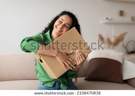 Shopping And Delivery. Contented Woman Buyer Hugging Cardboard Box Sitting On Couch At Home. Female Customer Being Happy About Delivered Package From Shop. Shopaholism And Commerce Concept Royalty-Free Stock Photo #2108470838