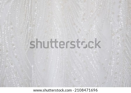 Close up shot at the white luxury gown textile dress with the glitter pattern detail that using with women bride. fashion and clothing background concept. 
