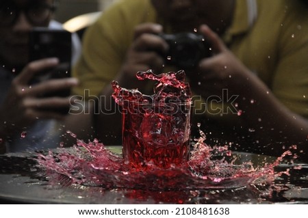 Noisy concept and selective concept of people taking picture of splashing Strawberry soda on the table