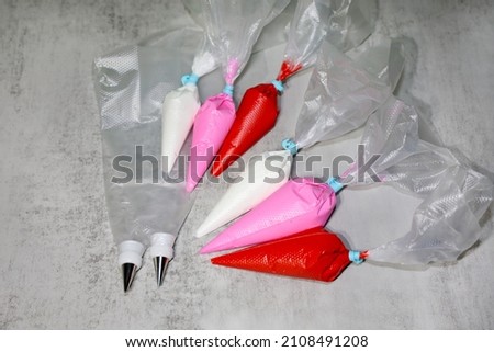 Piping bags with tips and couplers and colorful royal icing in piping bags with ties for decorating sugar cookies.