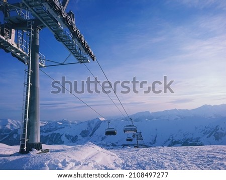 View of ski lift at ski resort with gorgeous snowy peaks at sunset