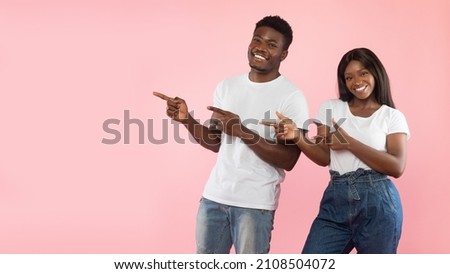 Check This Great Offer. Portrait Of Smiling Black Guy And Lady Pointing Fingers Aside At Free Copy Space, Couple Demonstrating Empty Place For Advert Mockup, Pink Studio Background, Panorama Banner