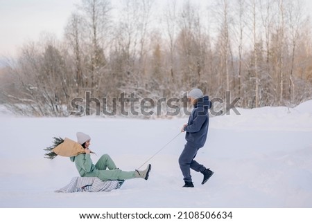 Smiling man giving sledding ride to woman. Love and leisure concept. High quality photo