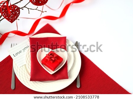 Festive table setting for Valentine's Day  or  Wedding day  with cutlery, gift box and hearts on white table. with card I love you on the plate. Space for text. Top view.