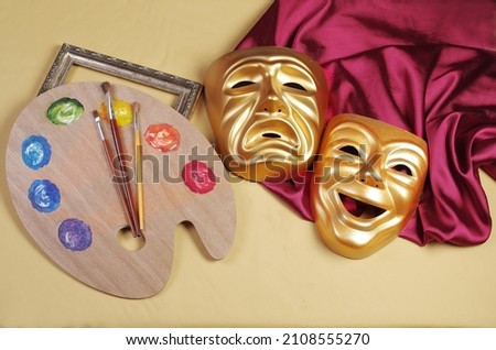 Art attributes.Theater, painting.Theatrical masks of tragedy and comedy, art palette, brushes and burgundy drapery on a yellow  background.