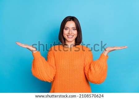 Portrait of attractive cheerful brown-haired girl holding on palms copy space ad isolated over bright blue color background