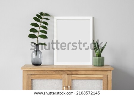 Blank picture frame mockup on white wall. Template for painting or poster. White living room interior design. View of modern rustic style interior with artwork mock-up
