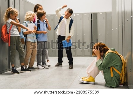 Angry cruel teenagers laughing at their classmate. Elementary school age bullying at school. Social inequality problem. Schoolchildren baiting Royalty-Free Stock Photo #2108575589