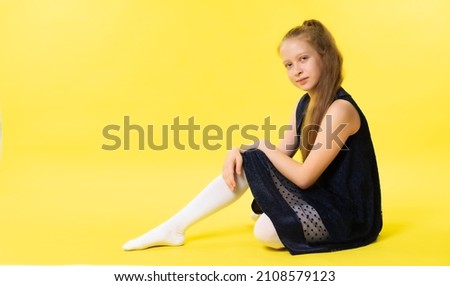 Portrait of a teenage girl in an elegant dress. Yellow background