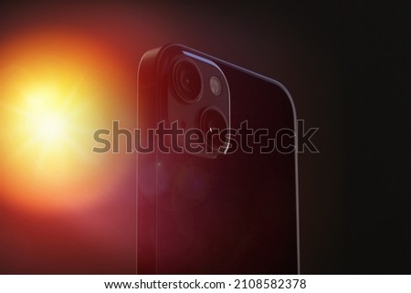 black modern stylish smartphone on with sharp square edges mi-e two cameras close-up on a gray isolated background with artistic yellow flare