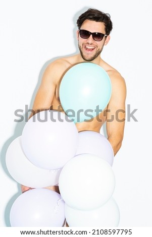 Handsome Caucasian Man In Sunglasses Impressed By Something Positive While on Party Or Club Presentation Wearing Contrasty Underware Outfit and Holding Bunch of Colorful Airballoons.Vertical image