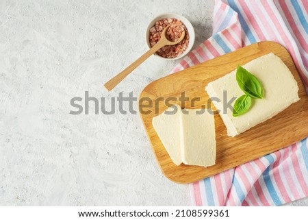 top view of tofu, paneer, soy cheese, curd cheese, brynza, feta, Adyghe cheesewhith pink salt on a wooden cutting Board on a light background, rustic style with copy space for text Royalty-Free Stock Photo #2108599361