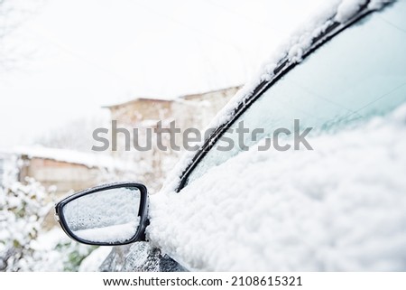 Cars covered with fresh white snow, close-up car side mirror, winter sky