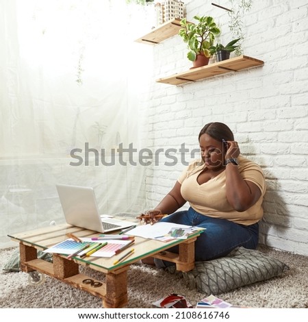 Female fashion designer drawing clothing model on paper during working at home. Young black focused millennial girl sit at homemade table. Concept of freelance and remote work. Modern successful woman