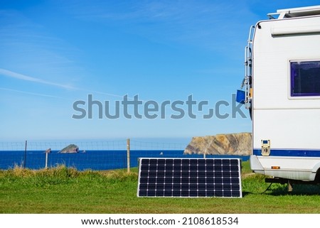 Portable solar photovoltaic panel, charging battery at camper car rv camping on spanish coast. Royalty-Free Stock Photo #2108618534
