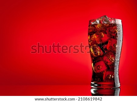 Cola with ice. Fresh cold sweet drink with ice cubes. Over red background with copy space Royalty-Free Stock Photo #2108619842