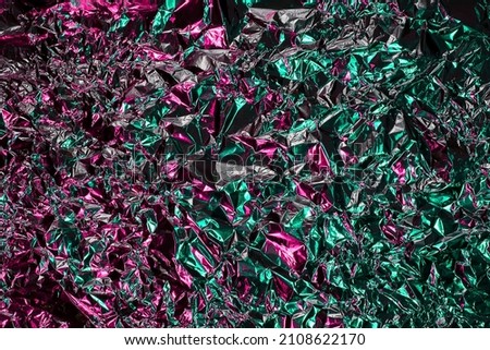 Green and pink aluminum wrinkled foil background. Abstract bright texture reflecting creative gradient. Light neon futuristic colors. Colorful shiny backdrop for screens, website, flyers and brochures