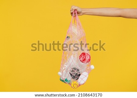 Close up cropped female hold in hand plastic bag with rubbish trash litter isolated on pastel plain light blue color wall background Environmental pollution concept. Copy space advertising mock up. Royalty-Free Stock Photo #2108643170