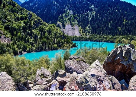 scenic view of the mountain lake and the slopes of the mountains covered with fir trees in sunny summer day. Horizontal photo of Issyk lake in Kazakhstan.