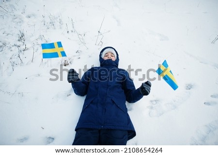 Scandinavian boy with Sweden flag in winter swedish landscape.