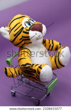New Year tiger cub on a purple isolated background. The tiger is a very beautiful and graceful animal. Keeps a gift in the saps