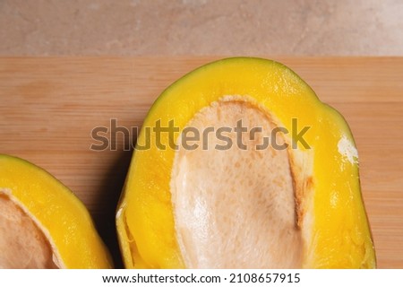 Cut a very ripe mango in half on a cutting board in your home kitchen. Yellow juicy tasty mango. Sweet tropical fruits for a vegetarian diet and healthy eating. view from above