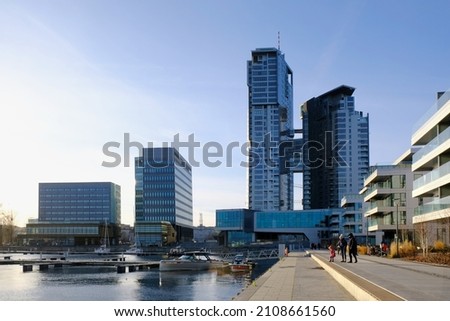Skyscrapers in Gdynia on  waterfront. Silhouettes of  walking family on shore of marina.