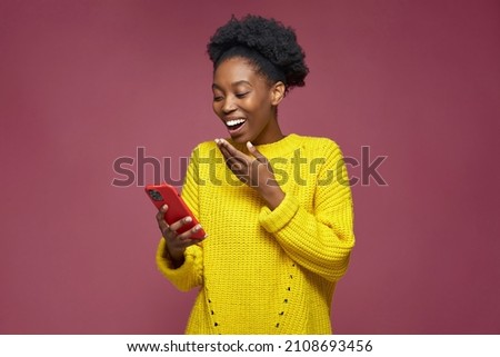 Laughing african american girl hold phone watching funny videos in social network, having fun, surprised by good news Royalty-Free Stock Photo #2108693456