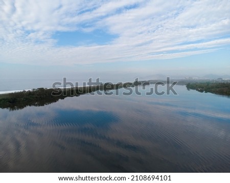 Aerial view of Reserva beach and Marapendi lagoon. In the background, the hills of Recreio dos Bandeirantes, in Rio de Janeiro, Brazil. Dawn. Sunny day with some clouds. Drone photo.
