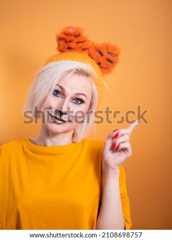 A girl with tiger makeup on an orange background. Funny smiling. Tiger new year celebration