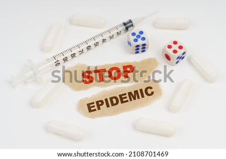 Medical concept. On a white surface lies a syringe, pills, dice and pieces of paper with the inscription - STOP EPIDEMIC