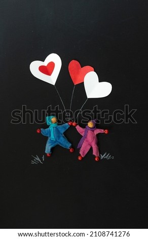 2 gender neutral characters holding heart balloons on a chalkboard background vertical, portrait orientation, black background, copy space