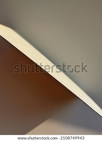 Paper edge. Sharp shadows from the sun on the table. One sheet on the table.
