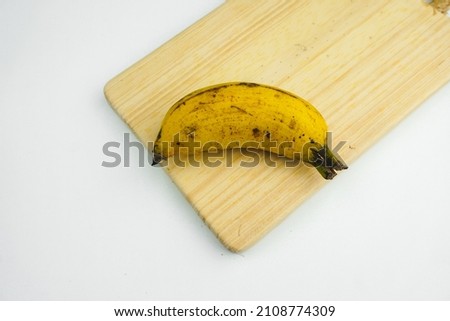 one banana on a wooden tray on a white background