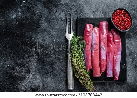 Fresh Raw lamb tenderloin Fillet, Mutton Sirloin Meat on marble board with thyme. Black background. Top view. Copy space