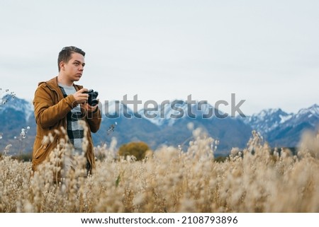 The man is a photographer in the field takes a picture on an old retro film camera.