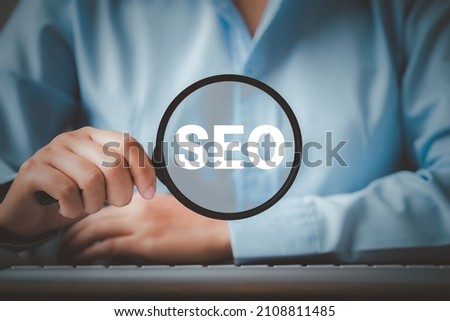 SEO Search Engine Optimization, Woman holding through magnifying glass with text SEO, concept for promoting ranking traffic on website, optimizing your website to rank in search engines. Royalty-Free Stock Photo #2108811485
