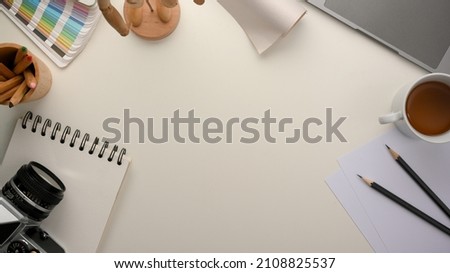 Graphic designer workspace with empty space on white table surrounded with work equipments. Top view, flat lay