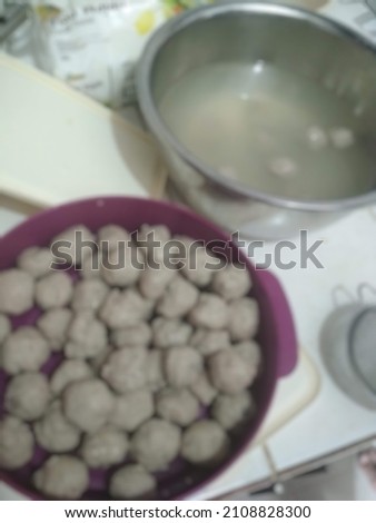 A picture of a big bowl full of meatballs and water. Abstract defocused blurry background