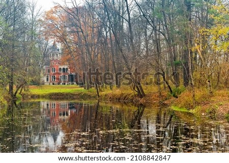 The western facade of Ghica Palace was built in a romantic architectural style from Dofteana, Romania. The reflection of the palace in the water of the lake surrounded by the trees in the park. 
