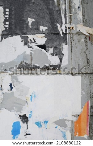 Vertical old street poster wall where the posters are torn off creating a layered creative arty paper pattern Royalty-Free Stock Photo #2108880122