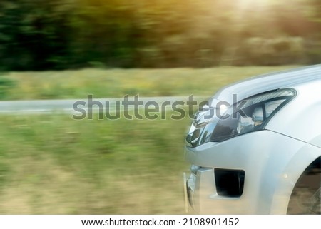 Front of silver car driving on the dust road. Speed motion of path parallels the asphalt road with a grassy background and a green forest. Drving for race. With copy space.